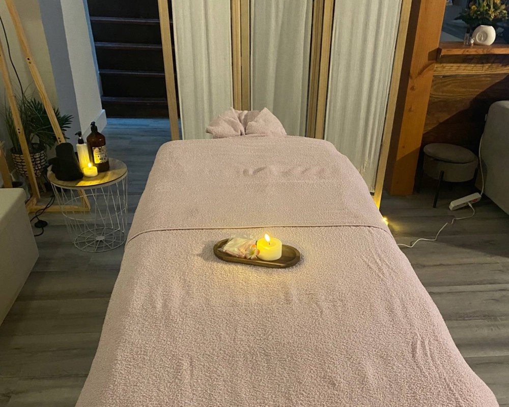 Table de massage installée à domicile, avec bougie allumée et huiles de massage à portée de main