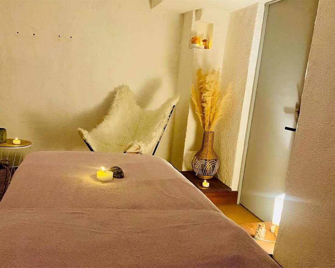 Le salon de massage à Oust : table de massage, bougies et fauteuil en fourrure